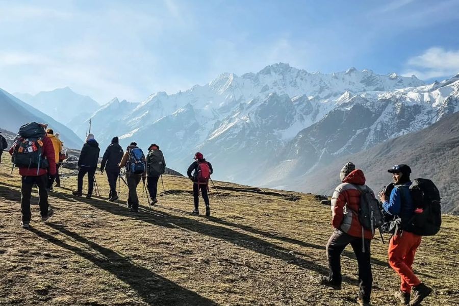 Trekking group gathered on alpine meadow with dramatic Himalayan mountain views
